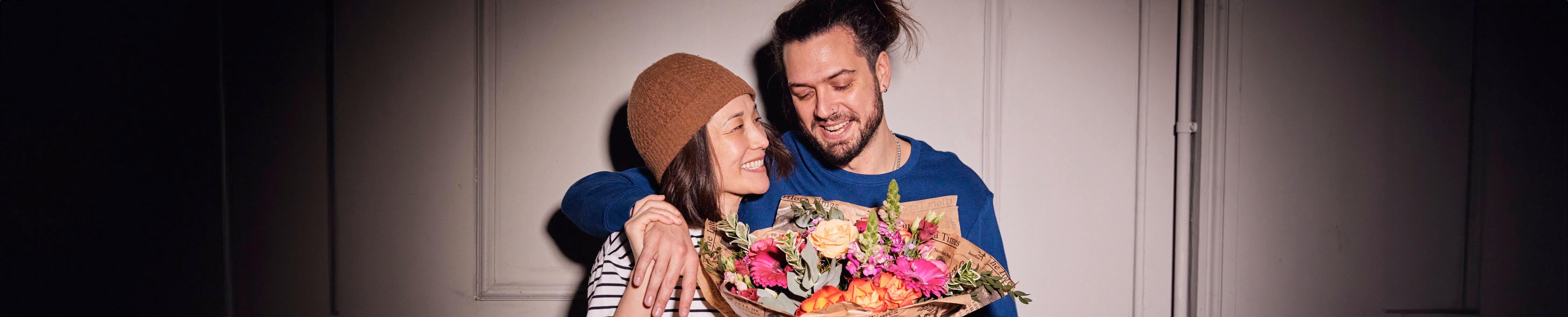 man-and-woman-smiling-with-bright-bouquet-flowers