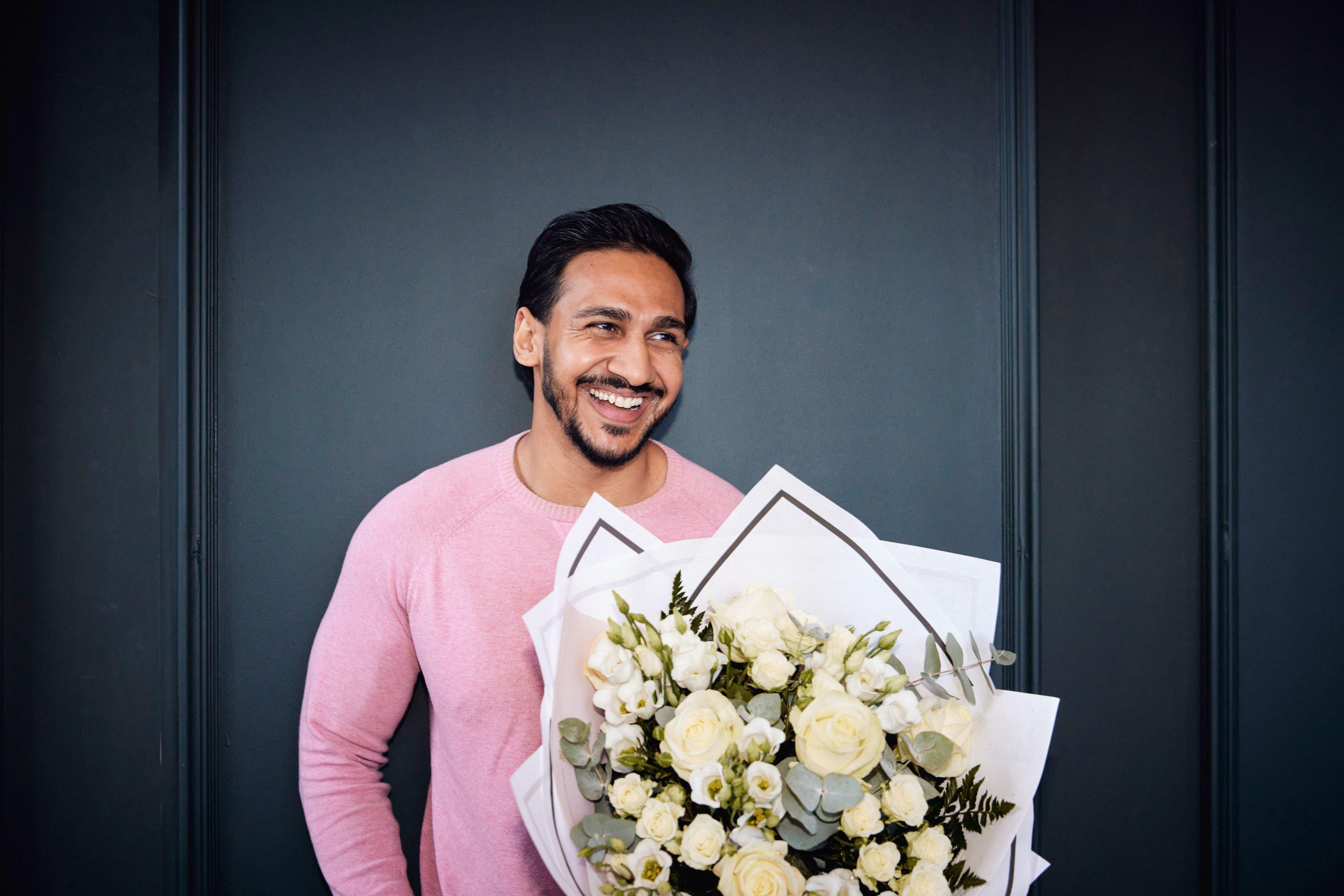 man-smiling-with-white-bouquet-flowers